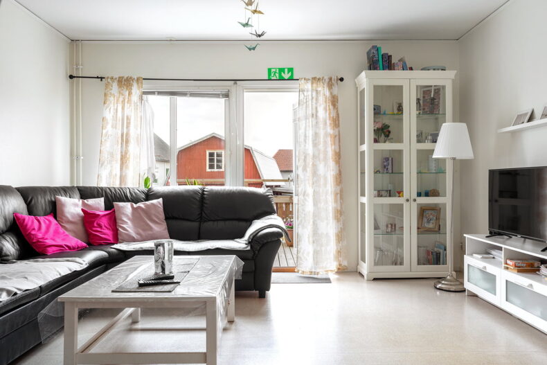 Gemensamt TV-hörn med stor soffa och dörr till altan.