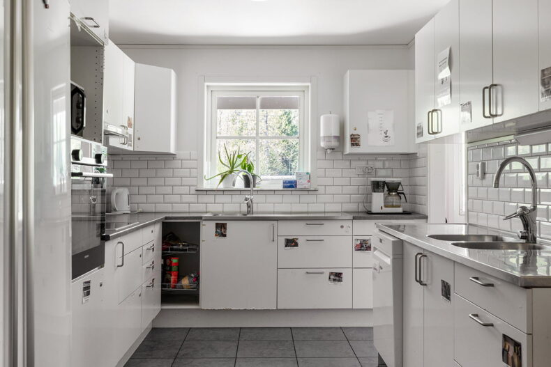 Kök med vita skåpsluckor och vitt kakel