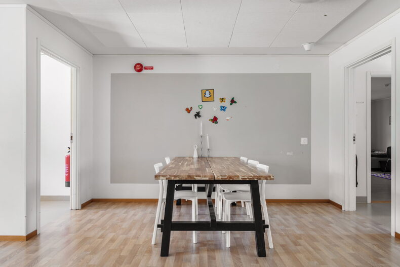 Matbord med vita stolar och färgglada pärlplattor hängandes på väggen bredvid
