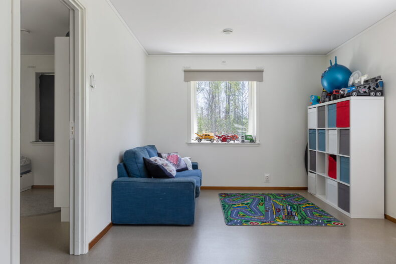 Mysig hörna med blå soffa och massa förvaring. I fönstret står leksaksbilar