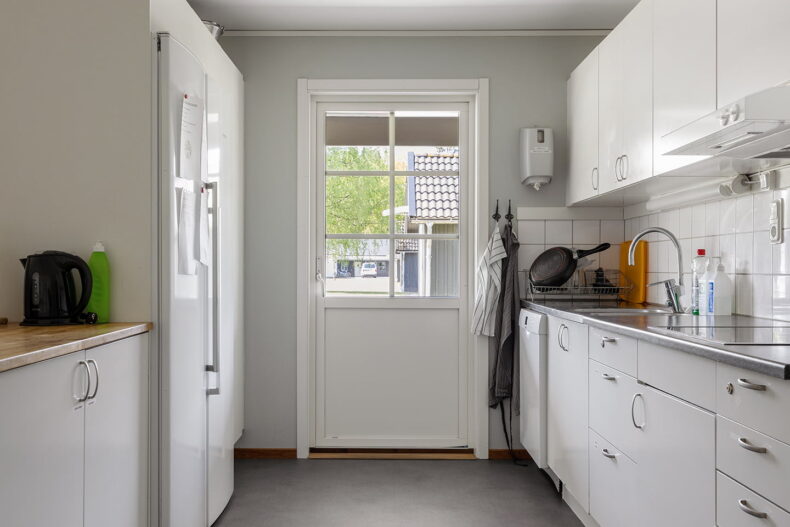 Ljust kök med vita skåpsluckor och vitt kakel