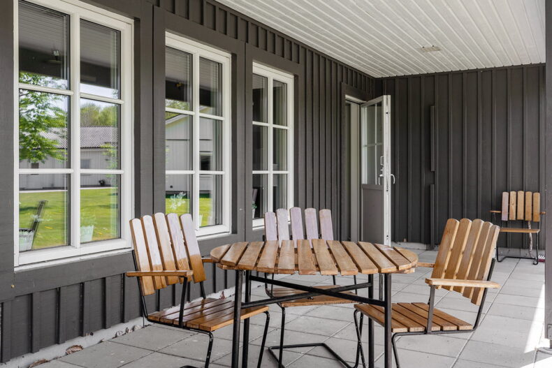 Uteplats med bord och stolar i ljust trä