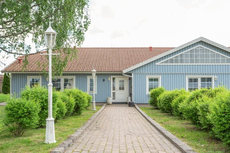 Den stenlagda gången fram till boendet, med buskar och gamla gatlyktor på sidorna