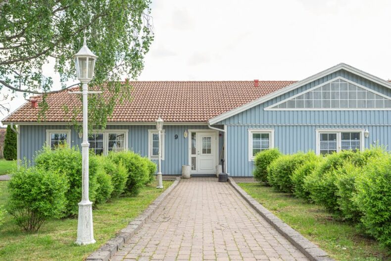 Den stenlagda gången fram till boendet, med buskar och gamla gatlyktor på sidorna