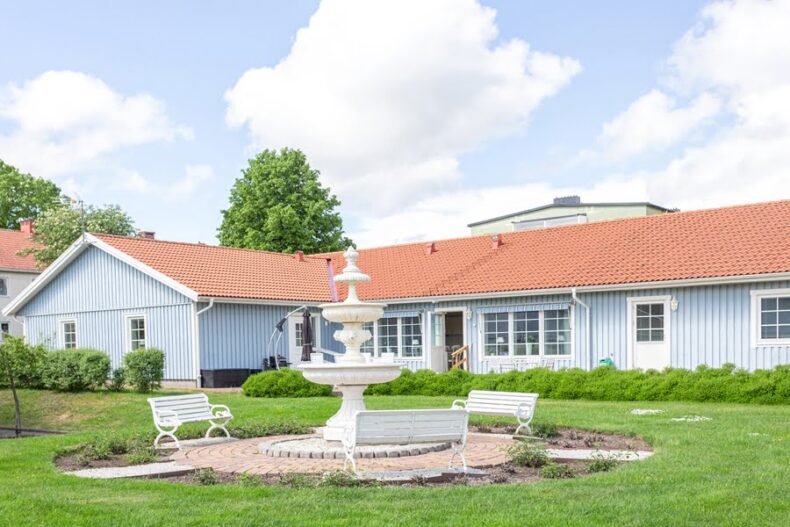 En fontän med parkbänkar runtom på boendets gräsmatta