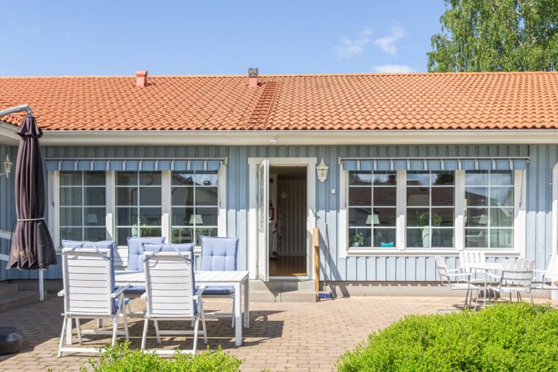 Boendets stenlagda uteplats med möbler och parasoll