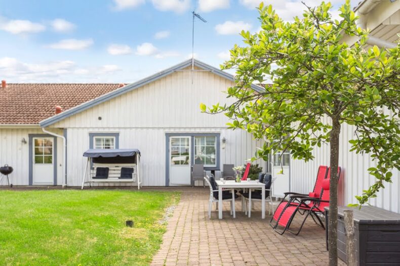 En stenlagd uteplats med hammock, solstol och utemöbler