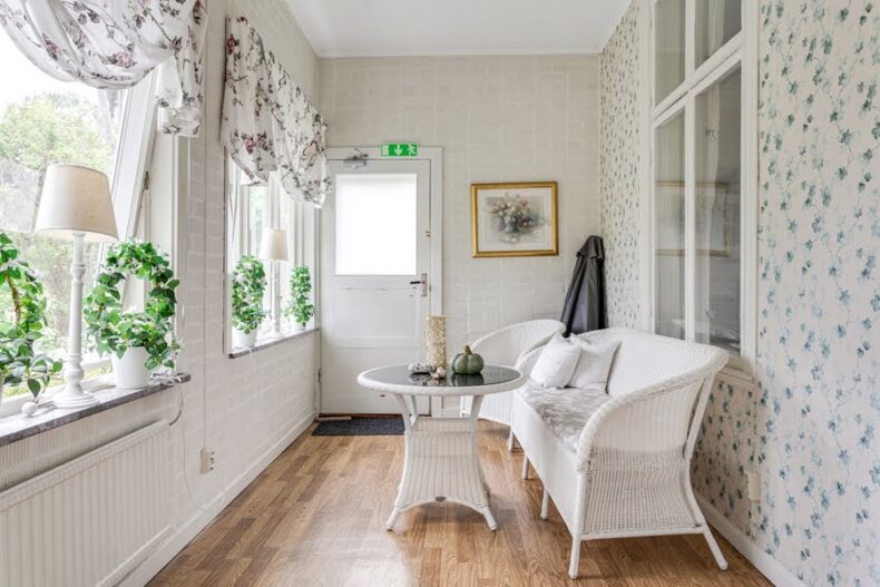 En hall med soffa, fåtölj och soffbord som vetter mot de stora fönstren