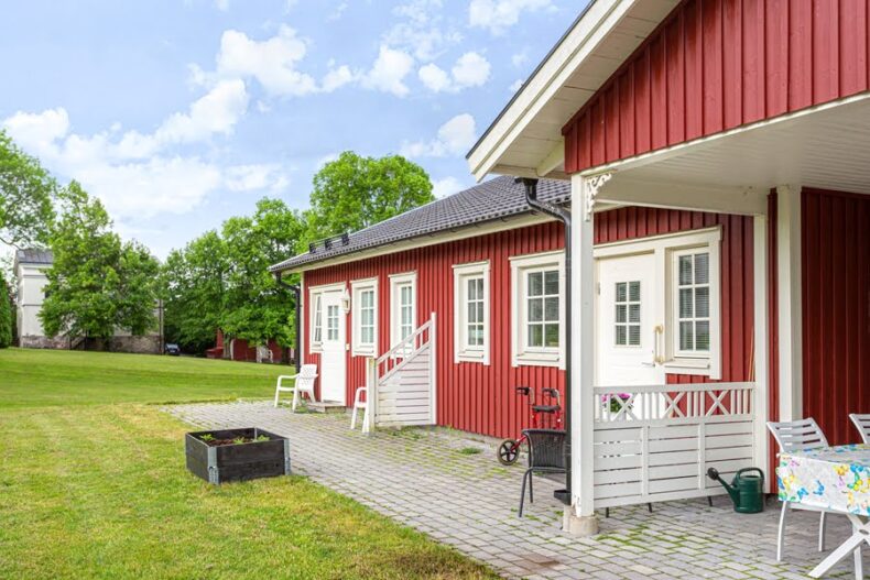 Stenlagda uteplatser utanför lägenheterna samt en odlingslåda på gräsmattan framför